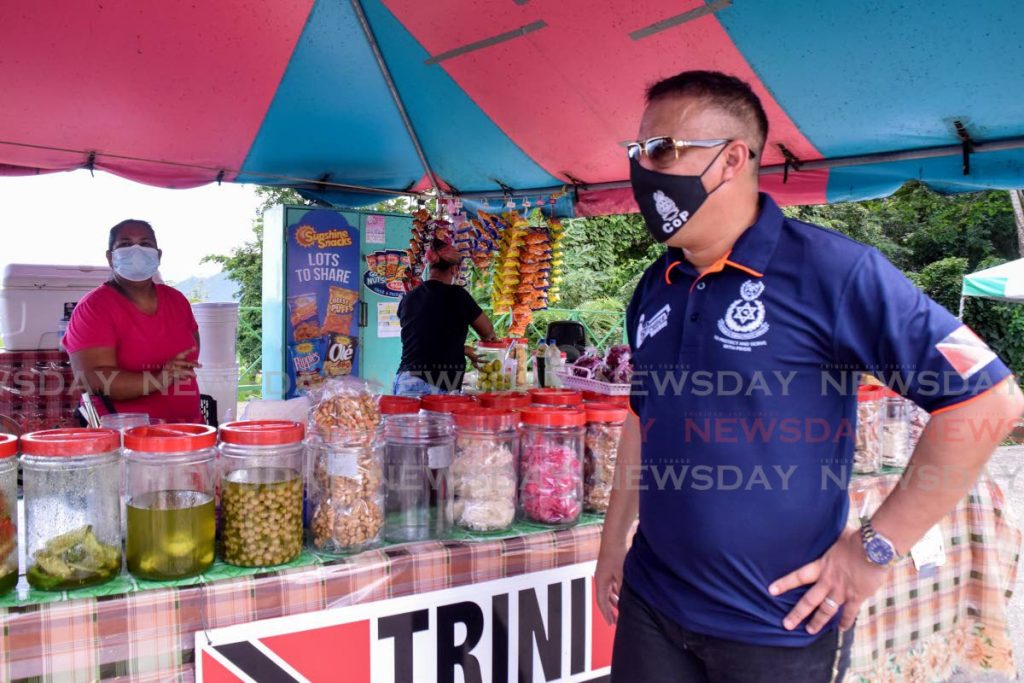 Commissioner of Police Gary Griffith observes business operations at one of the vending stalls at the Maracas lookout, North coast road, on Sunday morning. - Vidya Thurab