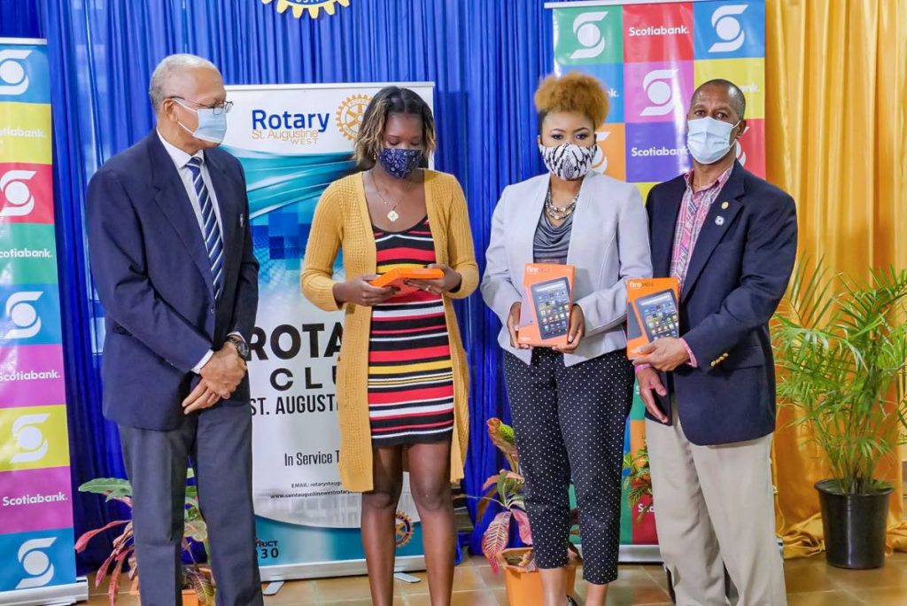 From left, past president of the Rotary Club of St Augustine West Stephan Gift, Tauriel Kelly, Education Minister Nyan Gadsby-Dolly and past president Adrian Saunders.  Kelly as given tablets for her children. The devices were donated by the Rotary Club of St Augustine West and the Scotia Bank Foundation on November 13. - 