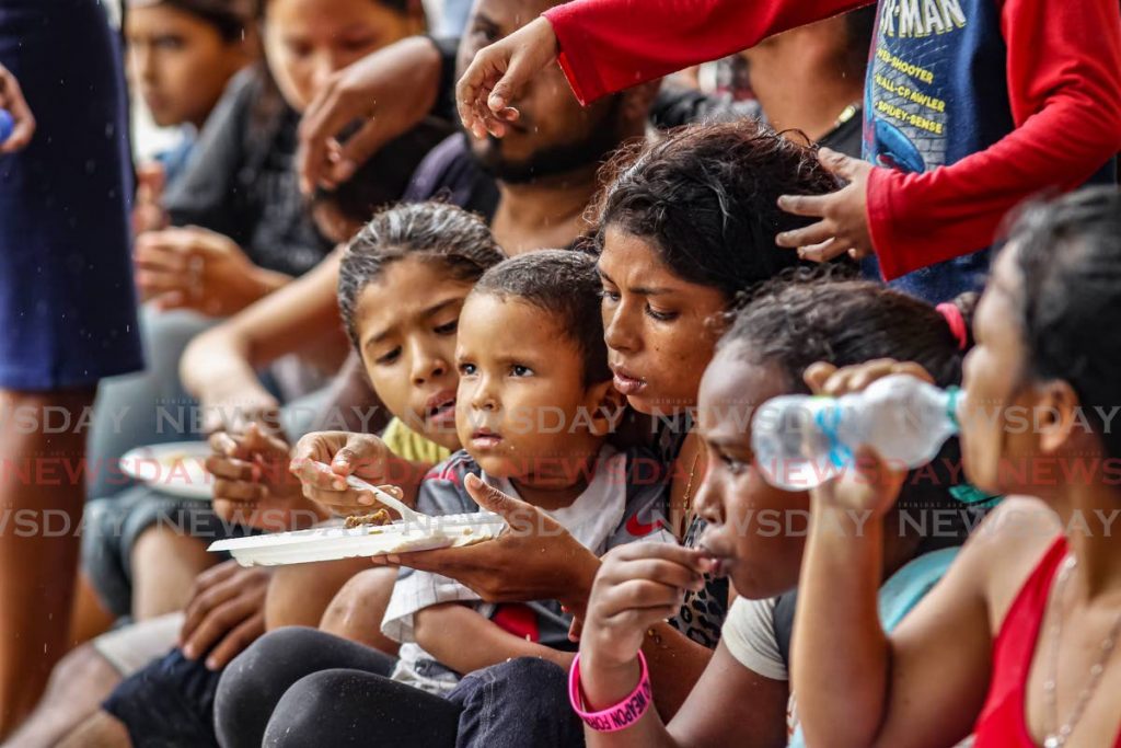 Venezuelans, many of them children, eat meals giving to them after arriving in boats for a second time at Los Iros, Erin on Tuesday. - File Photo/Lincoln Holder