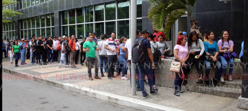 Venezuelans line up outside the Ministry of National Security in December last year to collect their registration cards to allow them to live and work in TT for one year. - 