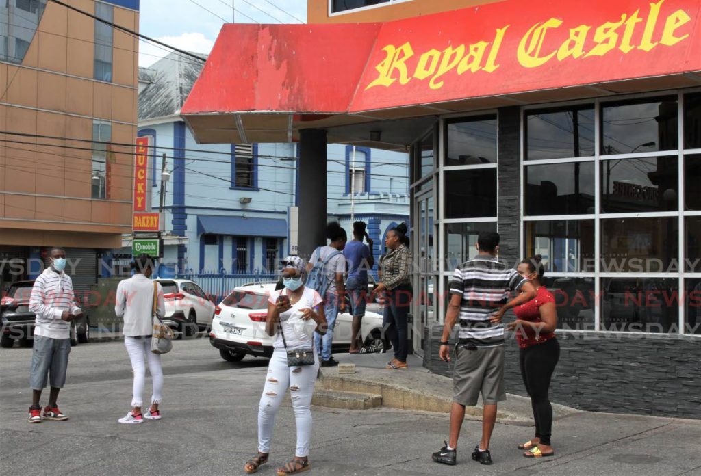 Fast food workers were among those who benefitted from salary relief grants from th government to help them pay their bills during the pandemic. In this file photo, workers gather outside Royal Castle Arima branch  to submit their applications in April. - 