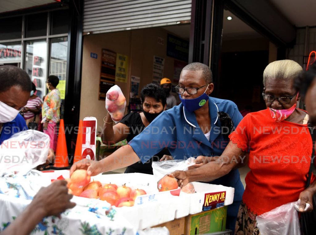 Customers buy apples at five for $10 on Charlotte Street, Port of Spain on November 26. Taxes on imported foods are due to increase from January, a measure that was announced in the 2021 budget in October. PHOTO BY AYANNA KINSALE - 