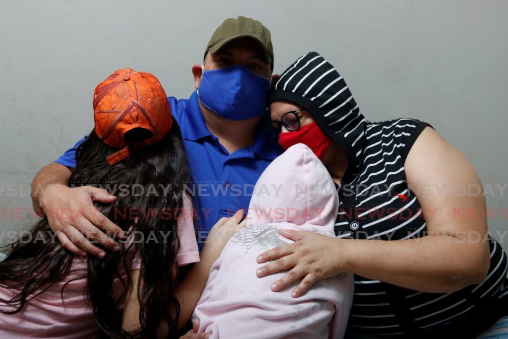  Dennys Hernández Lares embraces his wife and children in south Trinidad. Hernández Lares, a lawyer, was a director in the Social Christian party. Although he and his family entered TT illegally, Hernández Lares says migrants can contribute a lot to the country. PHOTOS BY MARVIN HAMILTON - 