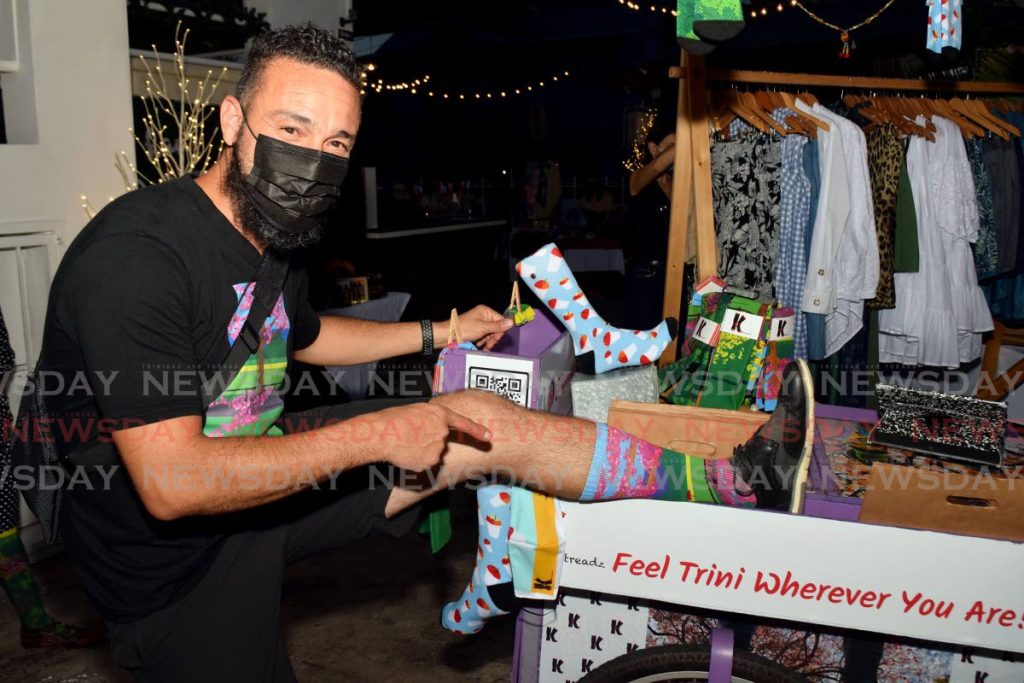Kamu Larid of Ktreadz models socks that feature his hand-drawn pictures of poui flowers at The Bungalow market on December 5. - 