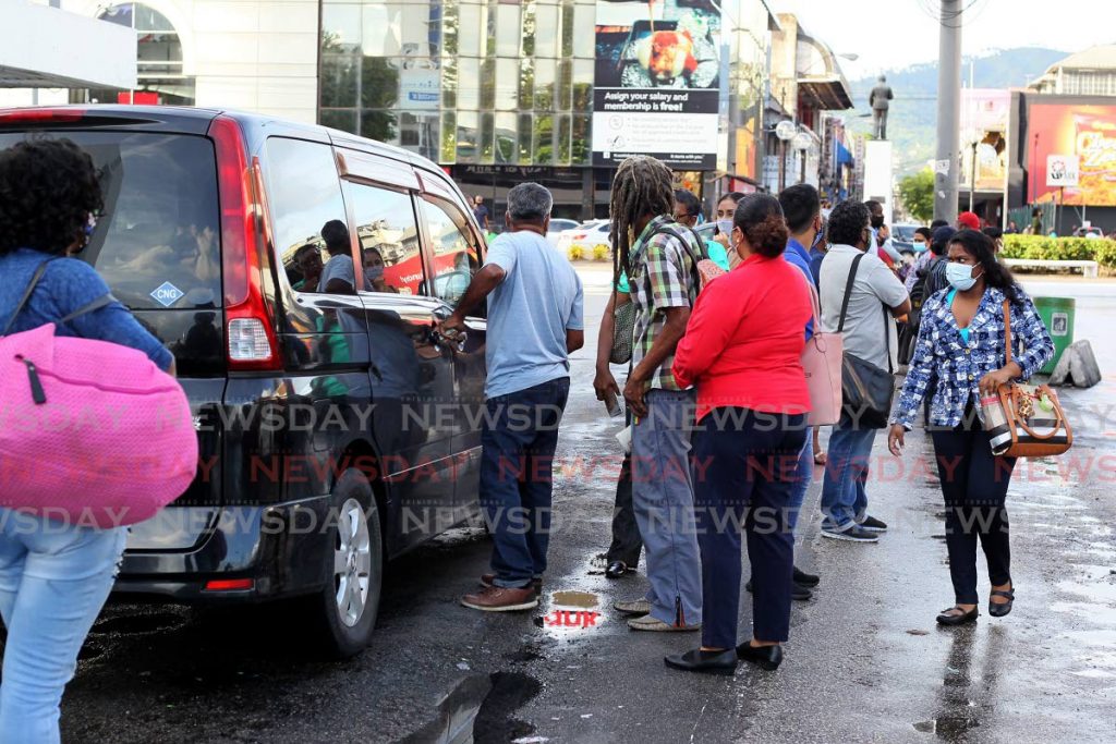Commuters crowd around a PH taxi on Broadway, Port of Spain, on Monday, when there were no licensed taxis on the Chaguanas and San Fernando stands at the time. PHOTO BY ROGER JACOB - 