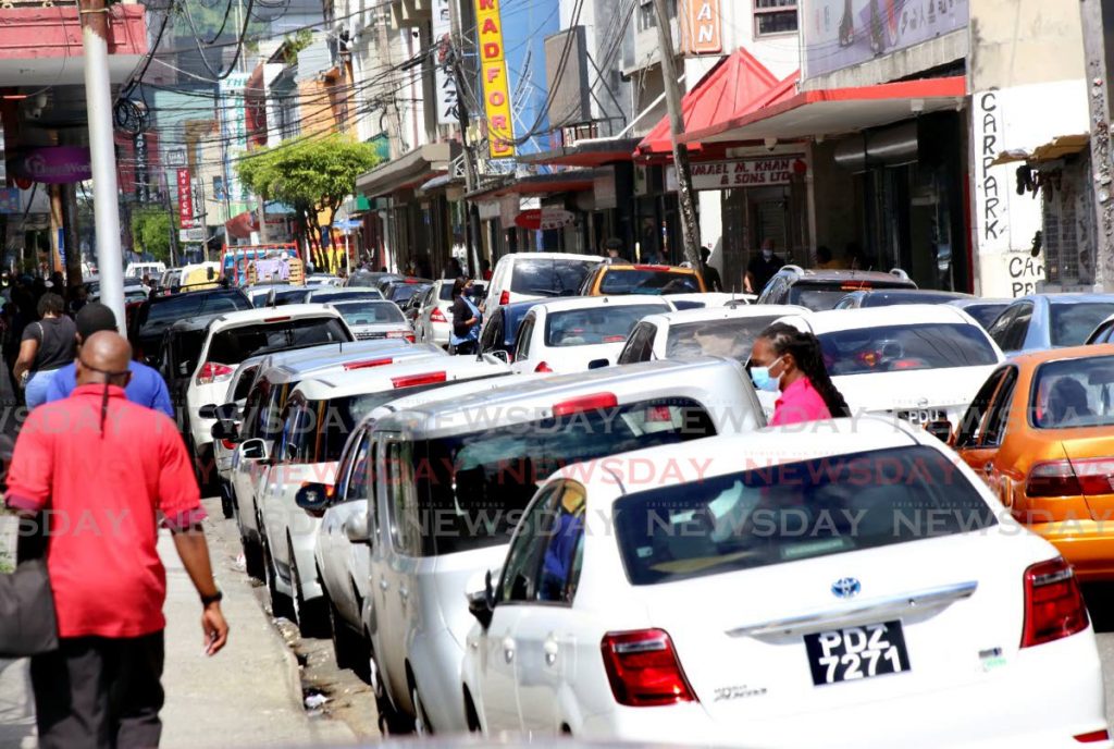 Pedestrians walk among cars parked and proceeding along Henry Street, Port of Spain recently. PHOTO BY SUREASH CHOLAI - 