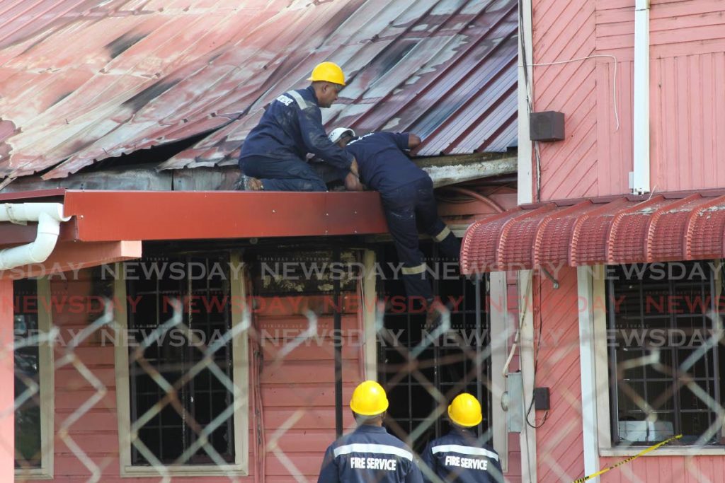 HAND UP: Fire officers at the scene of the fire which partially destroyed the office of Moruga/Tableland MP Michelle Benjamin early Thursday morning. - Lincoln Holder