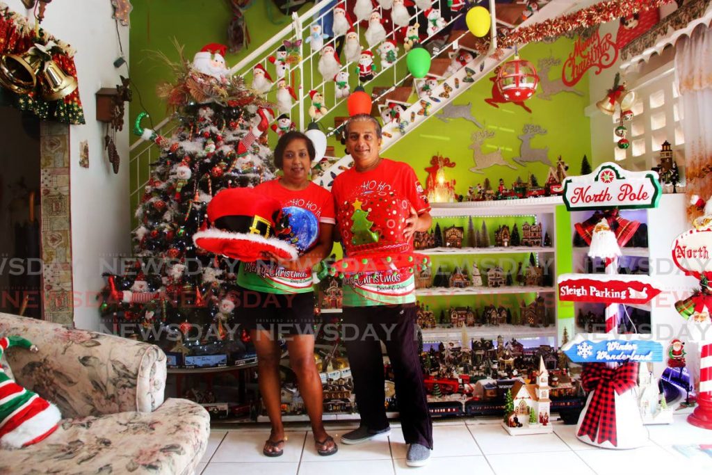 Dexter Kalloo with his wife Rampy Kalloo and their hundreds of pieces of lovely Christmas decorations including several toys trains that cover his whole living room at at his home in Diego Martin. - SUREASH CHOLAI