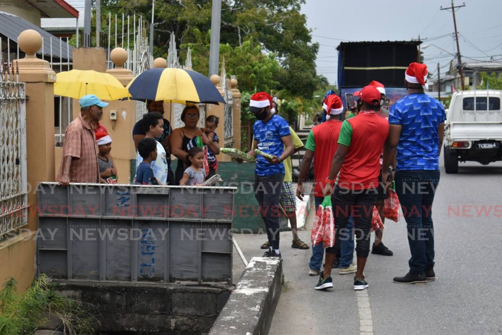 Mayor of Chaguanas Faaiq Mohammed, centre, and members of the Central Super League distribute toys and gift bags to residents of Charlieville, on Sunday. - 