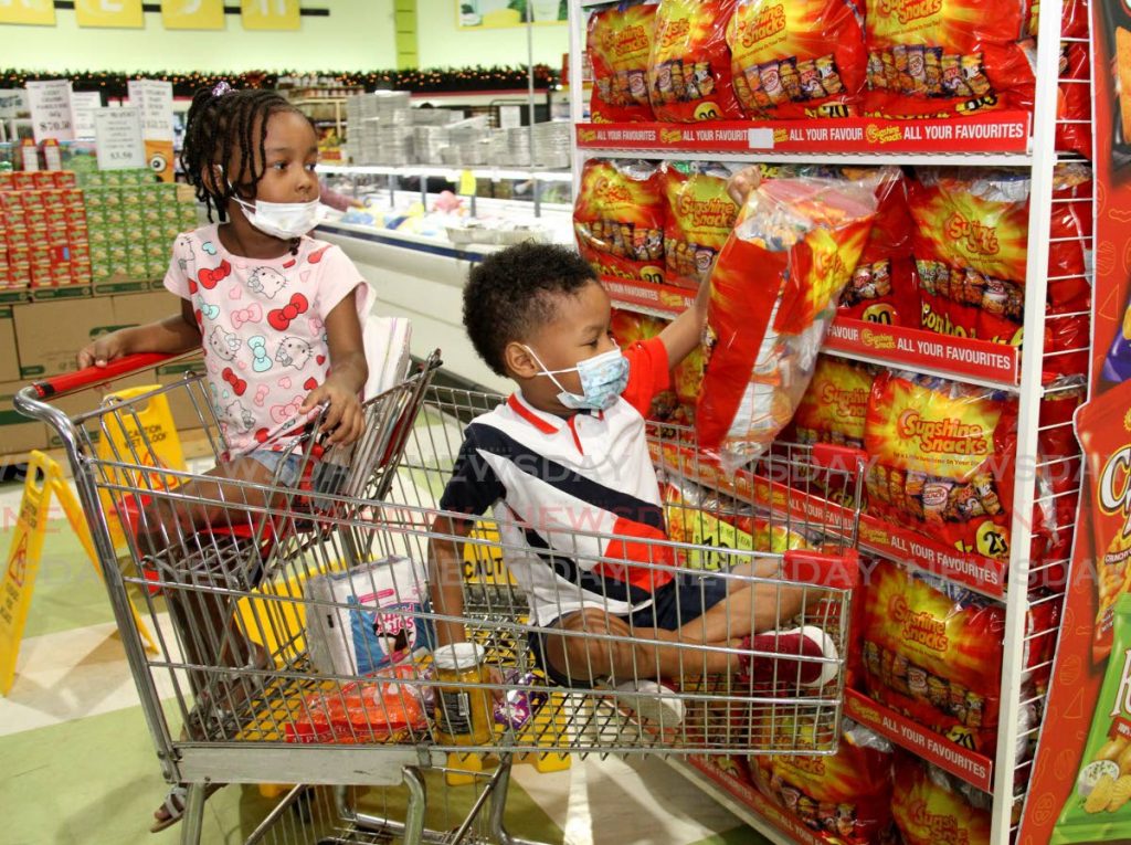 In this December 2020 file photo Kaileigh Thomas, 5, looks on as her brother Kai grabs a bag of snacks in Tru Valu Supermarket, Trincity Mall. The brother and sister were closely monitored by their mother. Photo by Angelo Marcelle