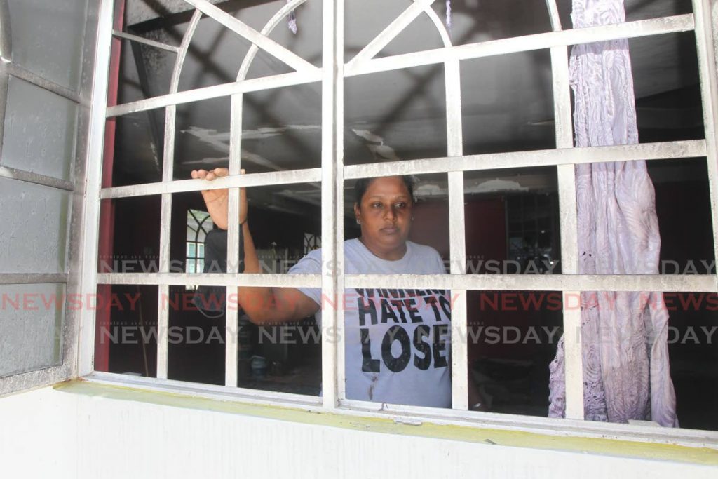  Runa Ali, 40 of Mc Bean Couva looks out her window after her home was gutted by fire one  year after it was firebombed.- Lincoln Holder