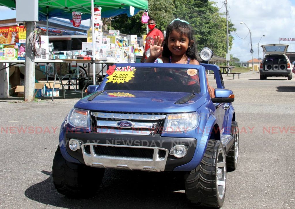 Four year old Hailey Bertrand test drives remote controlled operated car at a flea market at the Divali Nagar Site, Endeavour.  - AYANNA KINSALE