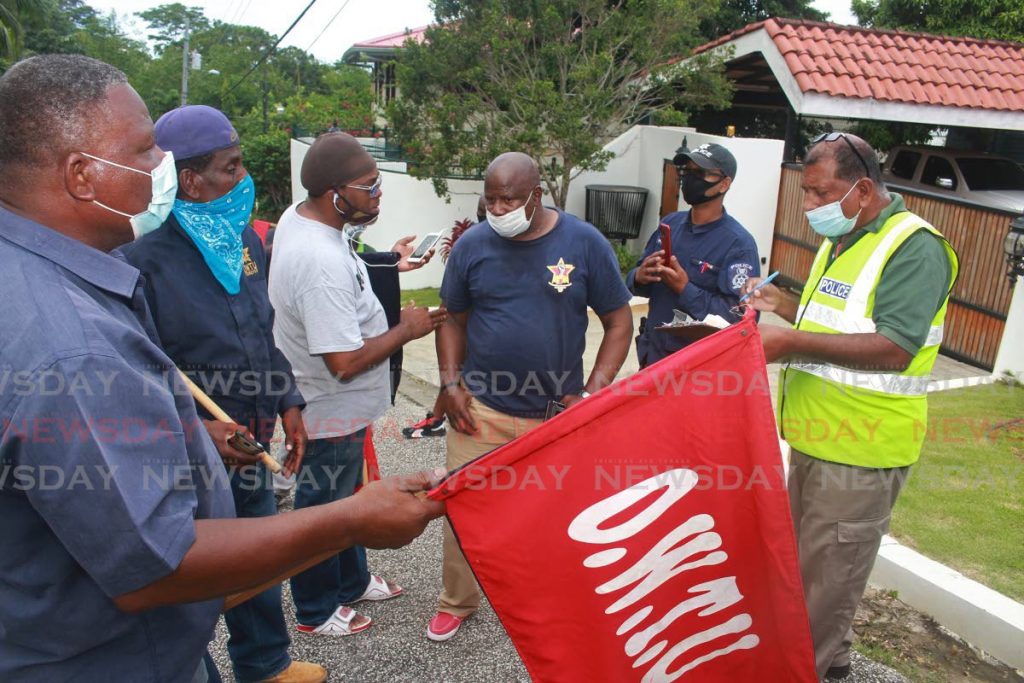 Ex-Lennox Petroleum workers explain their vexation to officer s, outside the premise of Wayne Persad's home on Christmas day. - CHEQUANA WHEELER