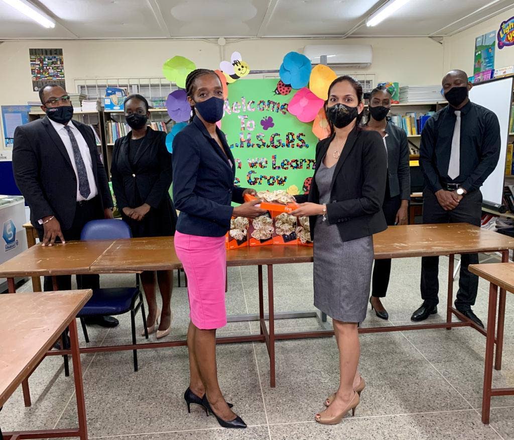 Chief Public Defender Hasine Shaikh, right, presents five tablets to principal of the La Horquetta South Government Primary School Denise Moore at the school on Monday. In background are other representatives of the Public Defenders Department. - Photo courtesy Public Defenders Department