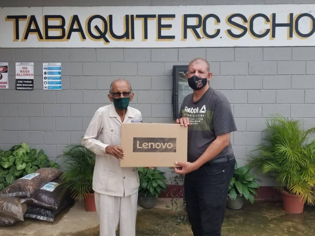 Professor emeritus Harold Ramkissoon presents one of the electronic devices to Gregory Subero, acting principal of the Tabaquite RC Primary School. - 