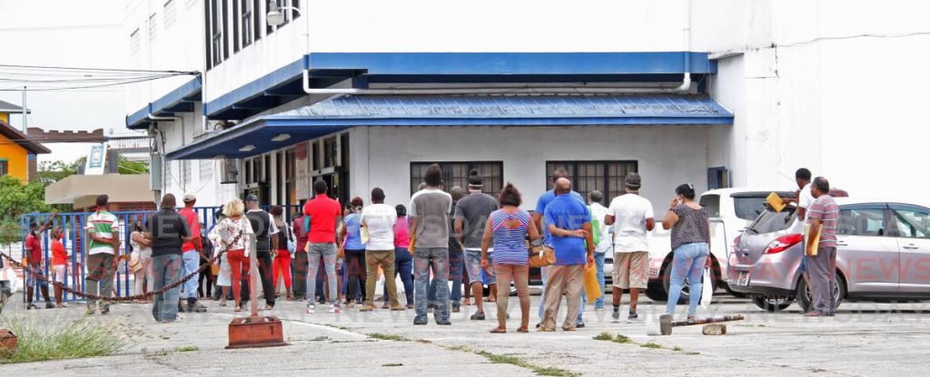 In this April 29 photo, people line up outside the Social Welfare office in Chaguanas hoping to collect covid19 relief grants offered by Government. - 