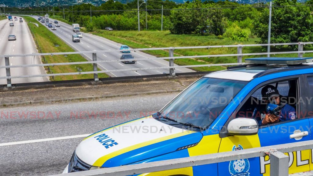 A Traffic and Highway Patrol Branch officer uses a speed gun while parked on the Caroni overpass to monitor the speed of vehicles on the north-bound section of the Uriah Butler Highway. (FILE PHOTO) - 