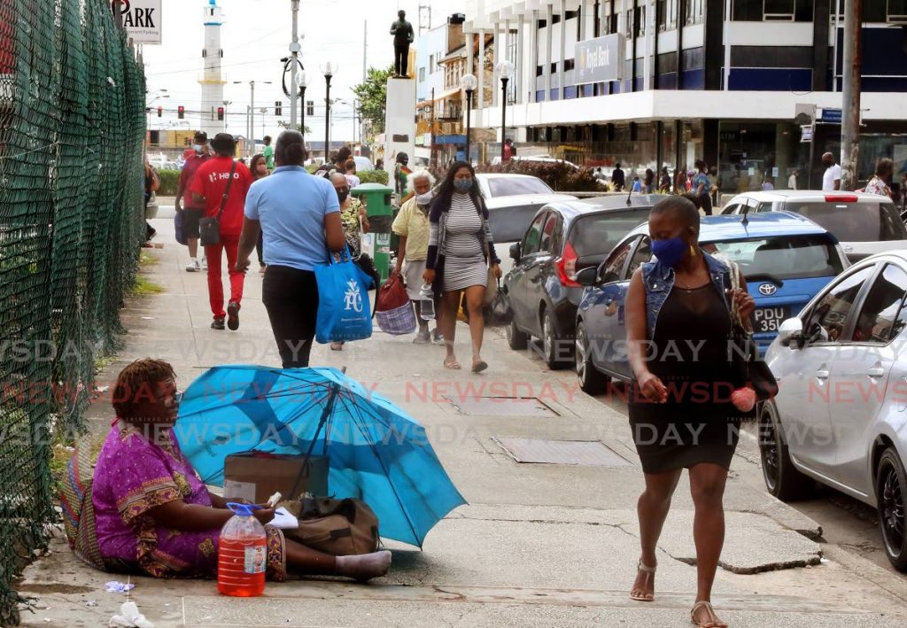 A pedestrian walks past a homeless woman on Frederick Street, Port of Spain, on November 25, 2020. - SUREASH CHOLAI