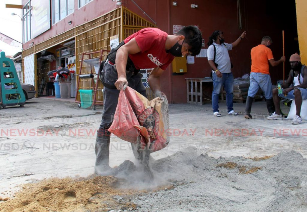 Employee Jose Lopez throws out a bag of Rock Hard cement to mix at at Second Crossing Hardware, Bon Air Gardens, Arouca on Saturday. PHOTO BY AYANNA KINSALE - 