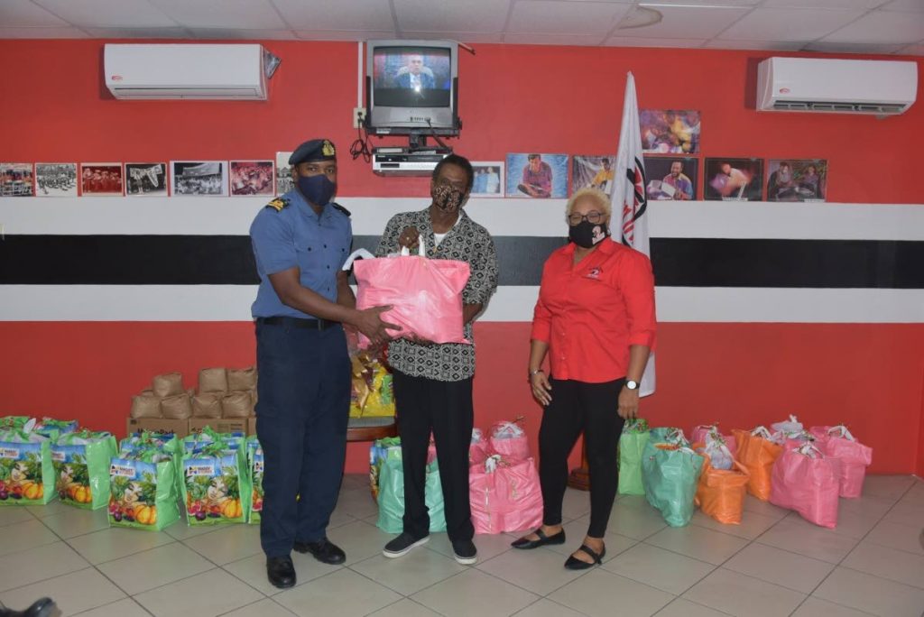 Lieut Sherron Manswell of TT Defence Force, left, presents a hamper to Anthony Kinsale from Laventille Serenaders Steel Orchestra, while Northern Region Pan Trinbago chairman Desiree Myers looks on. - 
