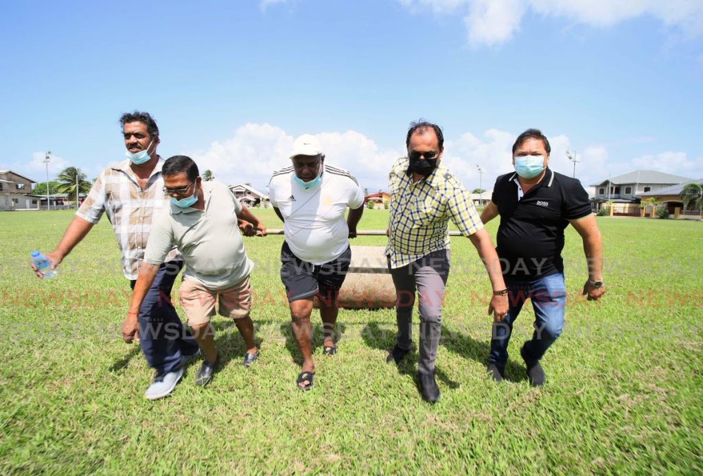 Central Sports president Richard Ramkissoon, right, and MP for Chaguanas West Dinesh Rambally, second from right, help groundsmen prepare the Central Sports ground in Chaguanas. Central Sports are hoping that the local cricket season will be allowed to resume soon.  PHOTO COURTESY TT CRICKET BOARD - TT CRICKET BOARD