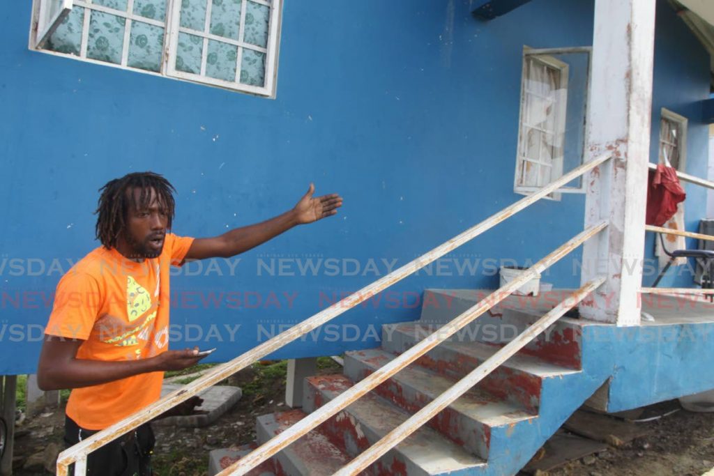 Chris Perryman makes a gesture toward the previously abandoned HDC house in Tarodale, San Fernando, that he's been occupying illegally with his two children for the past year. - Lincoln Holder
