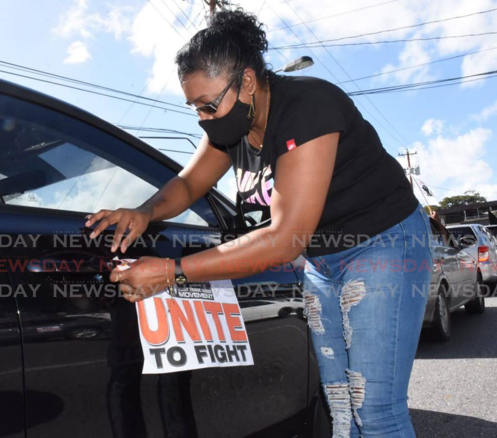 A trade union supporter sticks a Unite to Fight flyer on her car for the Joint Trade Union Movement/OWTU motorcade in San Fernando on Saturday. PHOTO BY CHEQUANA WHEELER - 