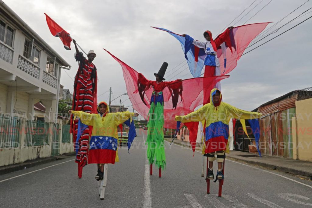 Moko jumbies in national colours of different countries walk along Henry Street, San Fernando. The Kaisokah School of the Arts uses the flags to show its solidarity with all nations affected by the covid19 pandemic. - 