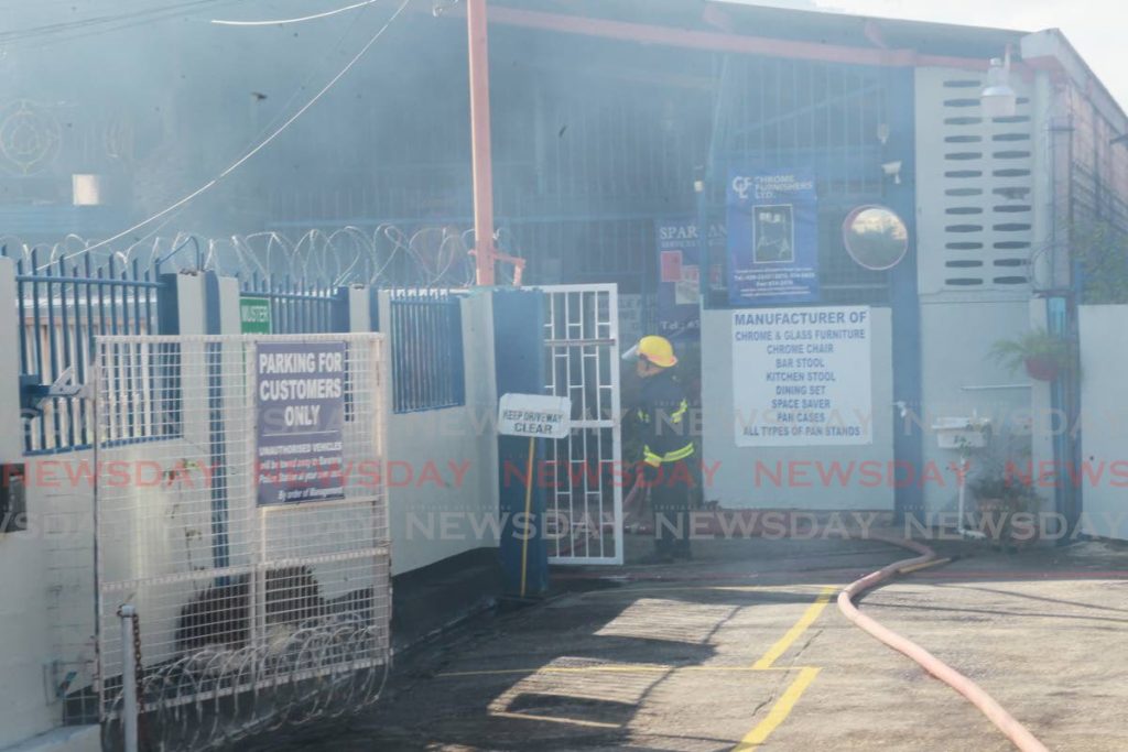 Firemen on the scene of the fire which destroyed Chrome Furnishers Ltd at Farouk Avenue, El Socorro on Wednesday.  - ROGER JACOB