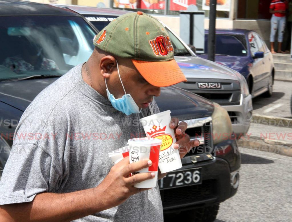 TAKING A SIP: A pedestrian removes his mask partially to take a sip of his drink in Arima on Saturday. Health officials are pleading with citizens to be vigilant and exercise greater caution as the UK variant of covid19 has reached our shores. - Angelo Marcelle