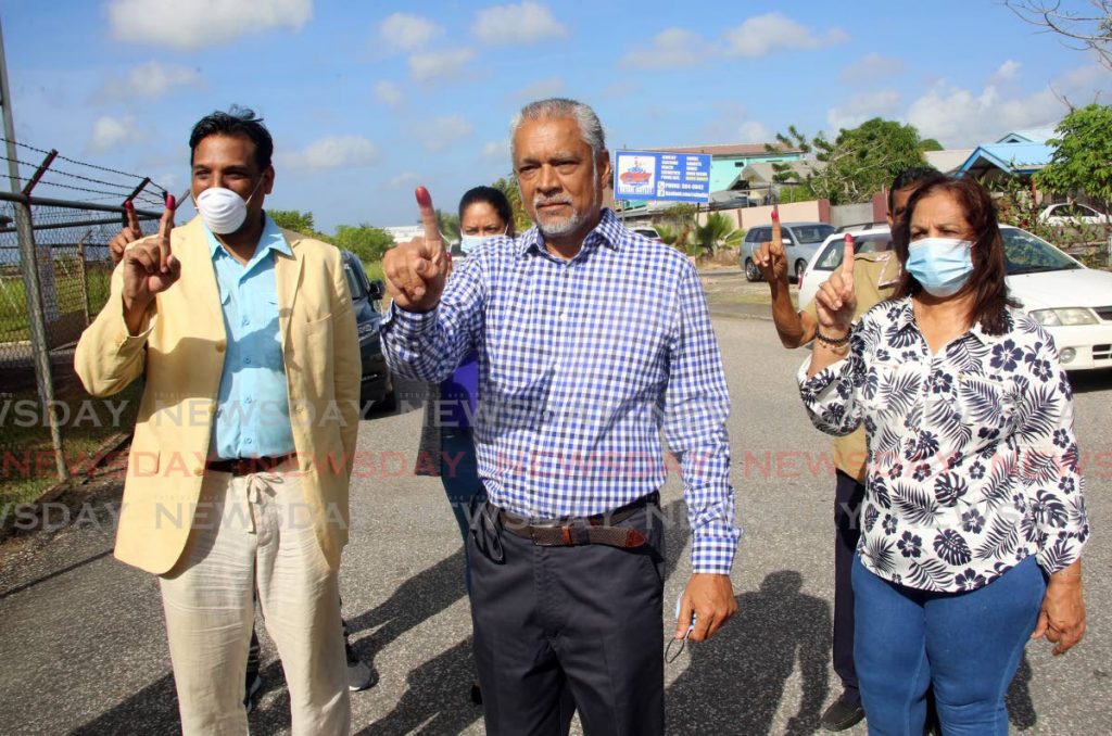 UNC candidate for Cunupia Richard Sukdeo, flanked by his wife on the right and UNC PRO Kirk Meighoo on the left, after he voted in the local government by-election at the Cunupia Secondary School on Monday. - SUREASH CHOLAI