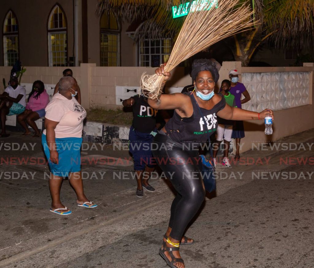 A PDP supporter dances with a broom in Roxborough on Monday evening. PHOTO BY DAVID REID - 