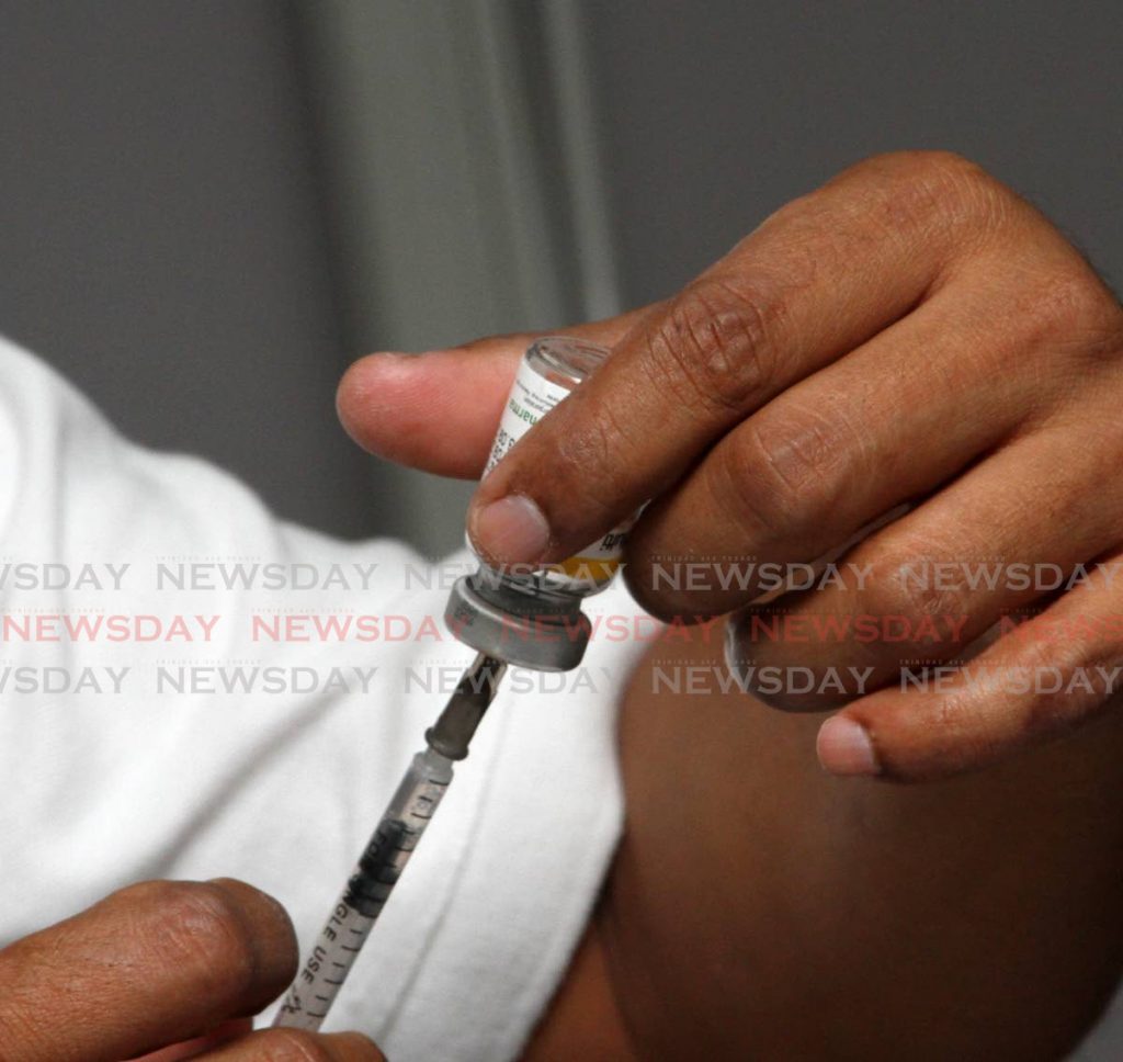 A healthcare worker prepares a dose of a flu vaccine. Some global health and political leaders have advocated giving the first dose of covid19 vaccines to as many people as possible before the second dose is given. - ANGELO MARCELLE