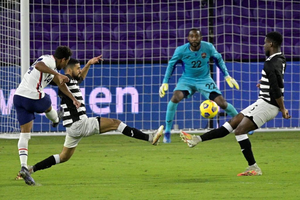 United States forward Jonathan Lewis (14) scores a goal between Trinidad and Tobago defenders Federico Pena, second from left, and Leland Archer, right, and goalkeeper Adrian Foncette (22) during the second half of an international friendly,on Sunday, in Orlando, Fla. (AP Photo) - 