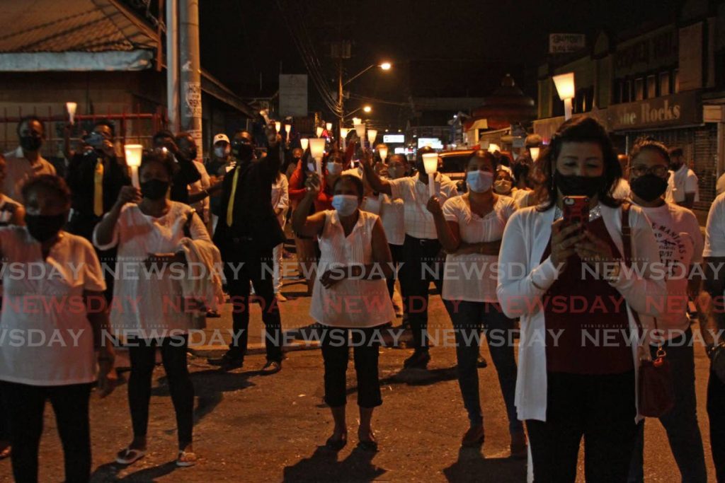 In this file photo, men and women hold candles and pray during a moment of silence for murder victim Andrea Bharatt during a vigil on  organised by the Concerned Citizens of Chaguanas and Environs outside the Chaguanas Market.  