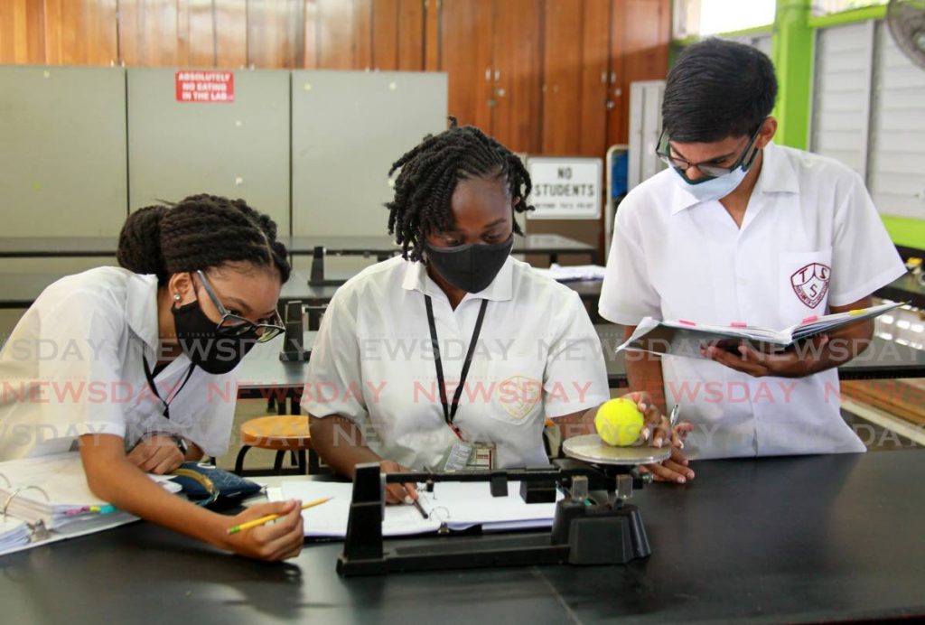 Form five students Rayanna Pantin, from left, Jada Mayers and Vivek Ragbir conduct a physics experiment on mass and kinetic energy in the laboratory at Tunapuna Secondary School. There is a movement to have more girls take part in science, technology, engineering and mathematics classes.  - ROGER JACOB