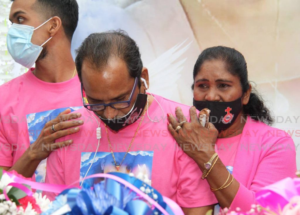 SORROW: Randolph Bharatt is supported as he looks at the casket of his murdered daughter Andrea at their home in Arima Old Road on Friday morning. PHOTO BY ANGELO MARCELLE - 