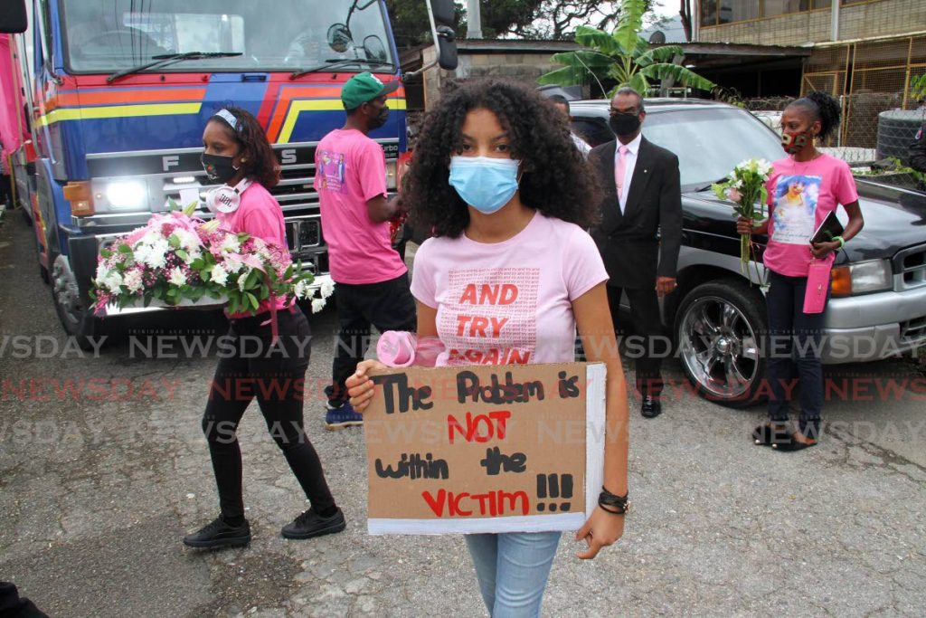 A young woman holds a sign, with a message against victim-blaming, outside Belgroves Funeral Home, Tacarigua where murder victim Andrea Bharatt was cremated on Friday. PHOTO BY ANGELO MARCELLE - 