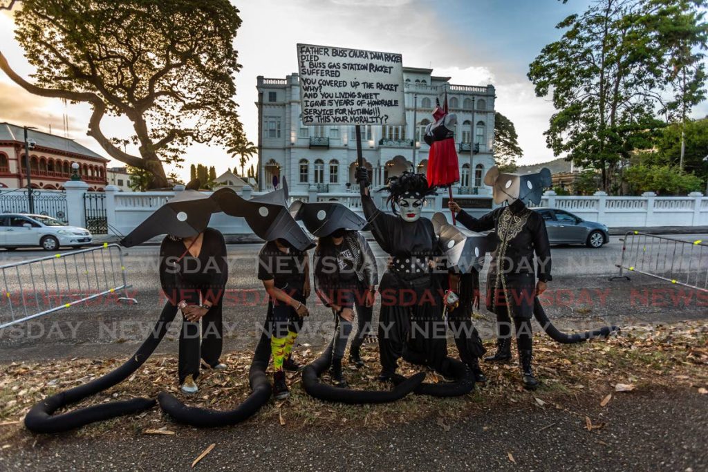 Cat in Bag Productions 2021 portrayal Rat Mas with Cecilia Salazar as Gene Miles (holding sign) taking part in the anti-gender-based violence march around the Queen's Park Savannah, Port of Spain. - Jeff K. Mayers