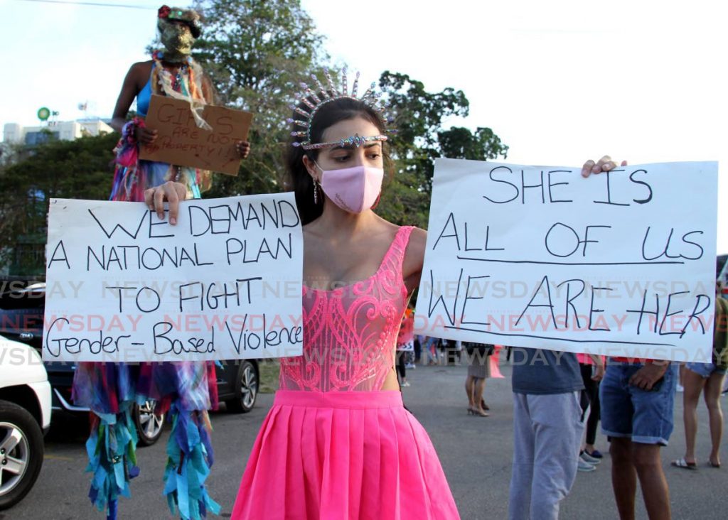 A costumed woman holds signs demanding a national plan on gender-based violence during a march by Women in Carnival around Queen’s Park Savannah, Port of Spain last Monday. PHOTO BY AYANNA KINSALE - 