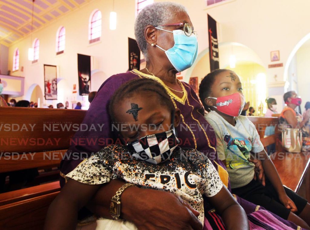 OUT COLD: Annette Hunte-Lessie with her grandsons three-year-old Eli Moore, who is fast asleep, 
and Jacob Moore, six, during Ash Wednesday Mass at Our Lady of Perpetual Help Church in 
San Fernando. PHOTO BY LINCOLN HOLDER  - 