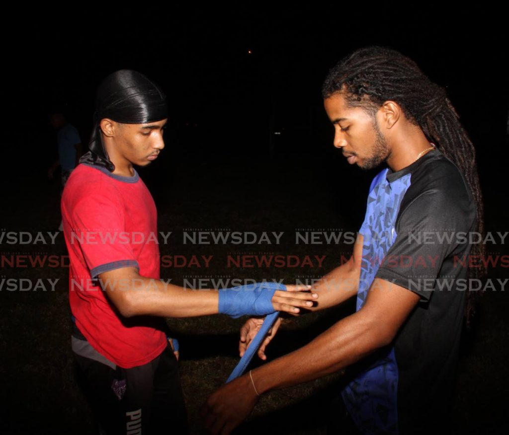 Jarel Nunes, right, wraps the hand of a young boxer before training. - Angelo Marcelle