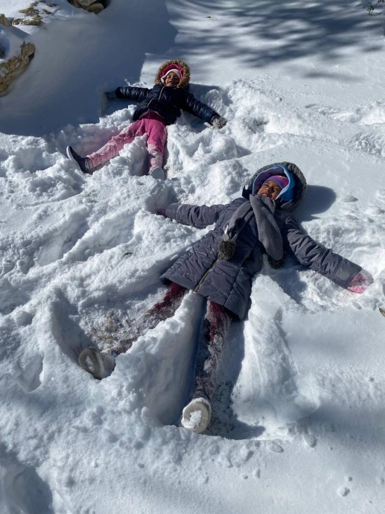 Malia Ramroop, five, and her sister Malini Ramroop, six, make snow angels in the yard of their San Antonio, Texas, home. Their parents Melissa Singh-Ramroop and Rohan Ramroop have Trinidadian roots and told Newsday about their experiences during the Texas snowstorm last week. PHOTO COURTESY RAMROOP FAMILY 
