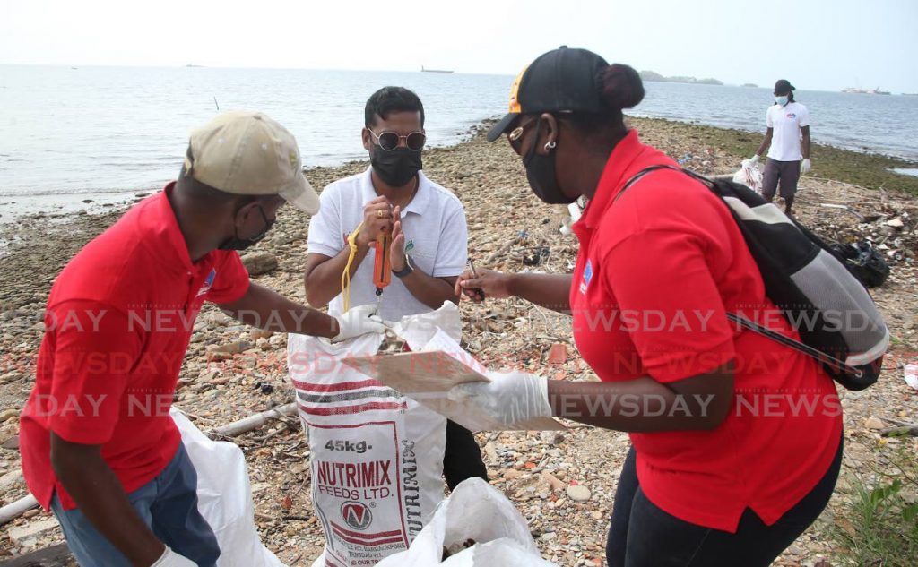 Ministry of Planning and Development senior communications officer Greta Joy Mc Kenzie, right, checks the weight on a bag of debris,  picked up during a coastal clean-up at the Carenage Fishing Centre, Western Main Road on Friday. The Ministry of Planning and Development, the European Delegation and the National Trust collaborated on the venture. - Angelo Marcelle