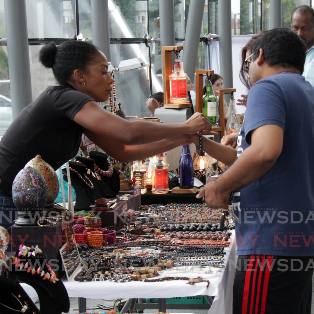 In this May 6, 2018 photo, a local female entrepreneur assists customers at the Festival of Fabulous Food and Finds in the National Academy for the Performing Arts lobby, Port of Spain. 