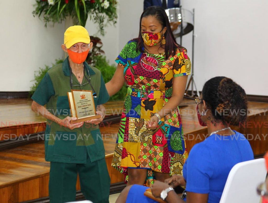 Maxie Andrew Assee is escorted to his seat by Adanna Antoine-Ramcharitar after receiving an award for outstanding community service at the official opening of the Arima community Centre on November 5, 2020. - Photo by Roger Jacob