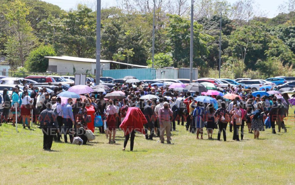 Scores of WASA employees gather at a muster point on the grounds of the authority on Farm Road, St Joseph on March 2 during an emergency evacuation after a fire alarm went off. The employees returned to work when the all clear was given. A Cabinet sub-committee report states the authority is overstaffed by 3,000. PHOTO BY ROGER JACOB - 