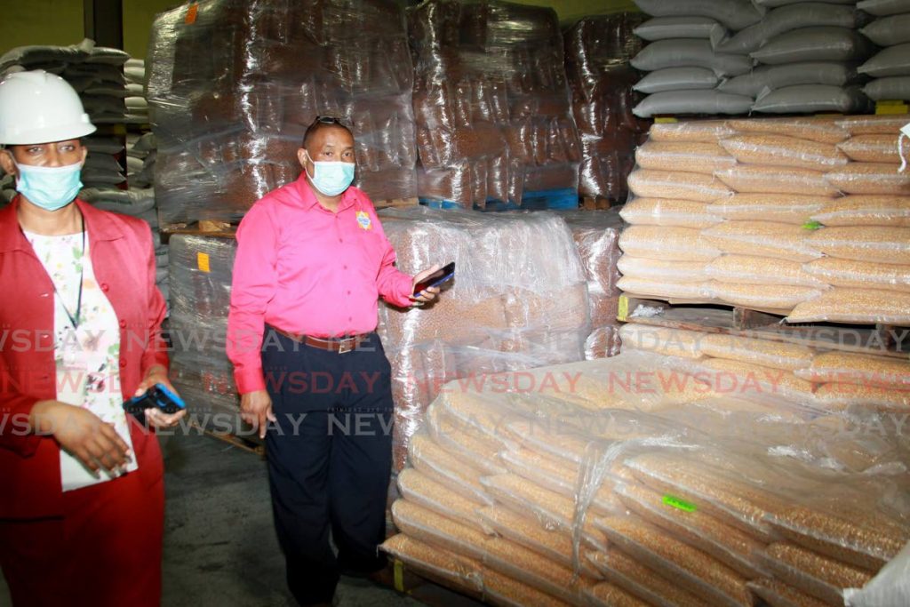 NFM feed supervisor Gary Hosang and corporate communications officer Lisa Cropper-Cudjoe inspect the animal grain supplies at the feed milling and packaging department on the Wrightson Road, Port of Spain compound on Wednesday.  - PHOTOS BY ROGER JACOB