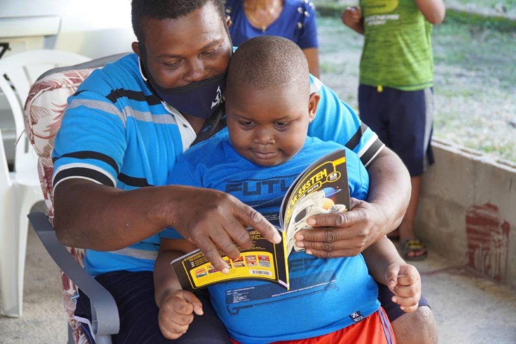 A parent and child share the joy of reading at the opening of the Matura Little Free Library. 