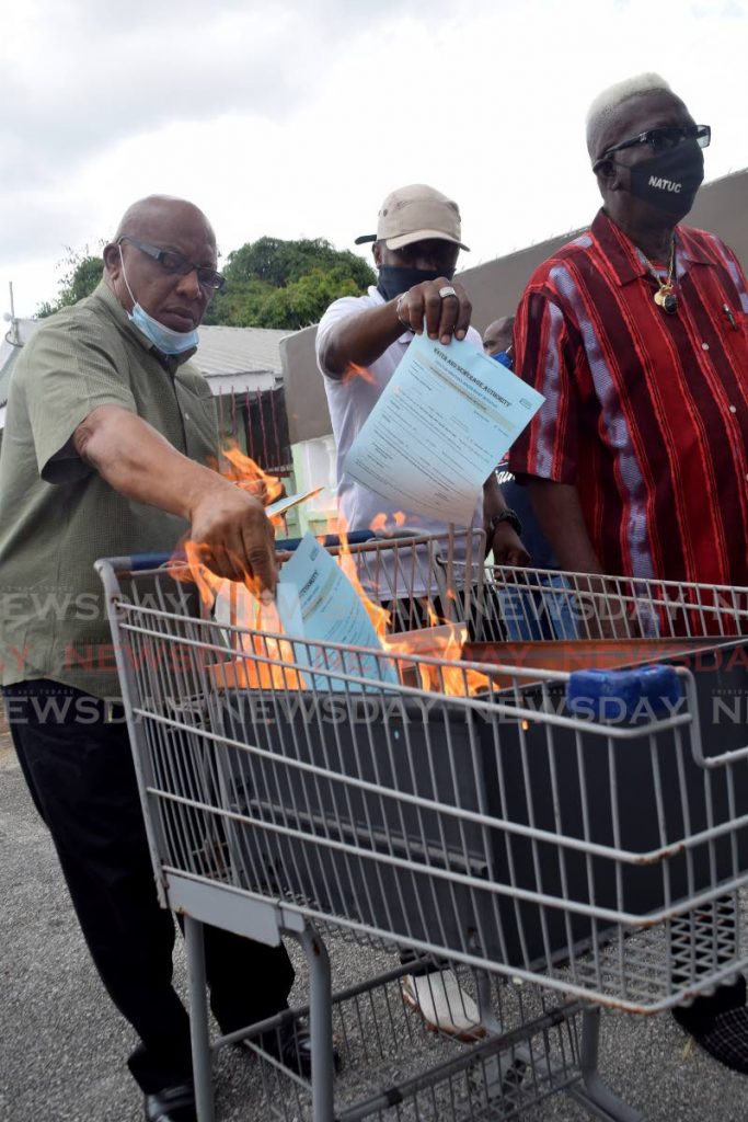 Daily paid worker Rodney Lewis, left, and another trade union member set fire to Executive Director’s Water Relief Fund forms at a press conference at NUGFW office, Henry Street, Port of Spain on Thursday. - Vidya Thurab